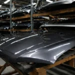 Capôs automotivos armazenados em prateleiras de distribuidora, destacando organização, qualidade e confiabilidade na compra de peças de lataria online.